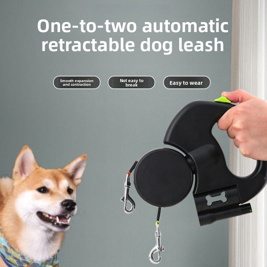 Hand holding a black Rainhound Double Retractable Lead with two clips beside a Shiba Inu